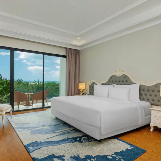 Luxury bedroom with a large bed, stylish headboard, and a view of greenery outside.